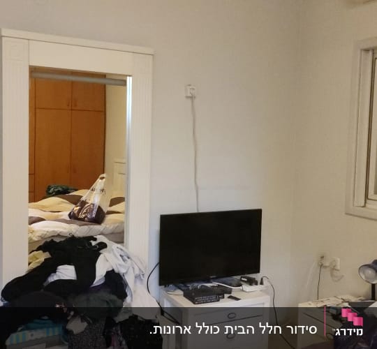 בגדים על שידה, טלוויזיה על שידה, מיטה עם מצעים